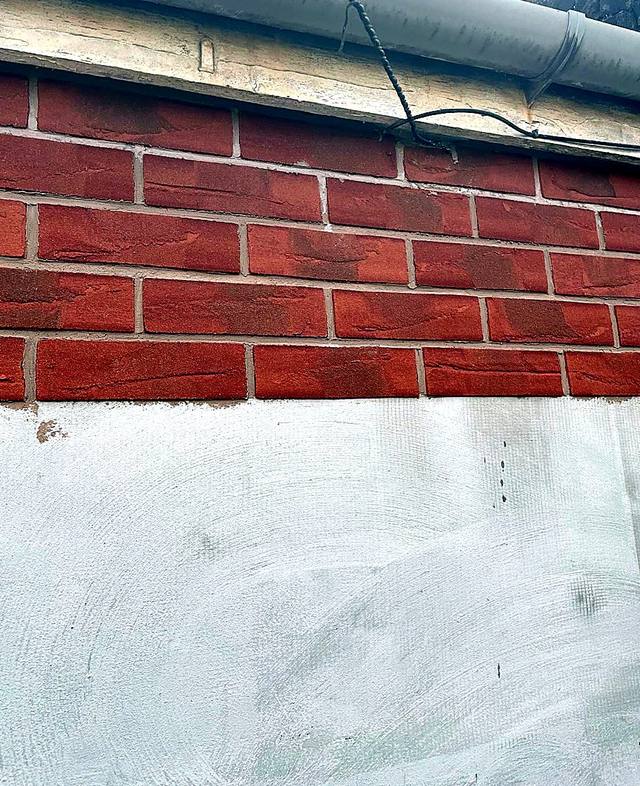 Red brick slips being applied above a rendered wall in the West Midlands