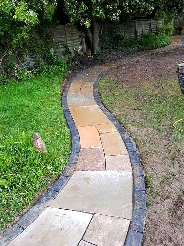 Curved sandstone garden path with dark edging through a lawn in the Wolverhampton area