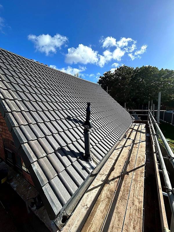 New grey interlocking roof tiles with dry verge and a flue vent in Halesowen