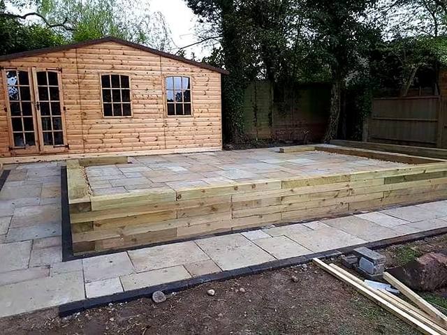Sandstone patio with sleeper raised beds in front of a summerhouse in the Wolverhampton area