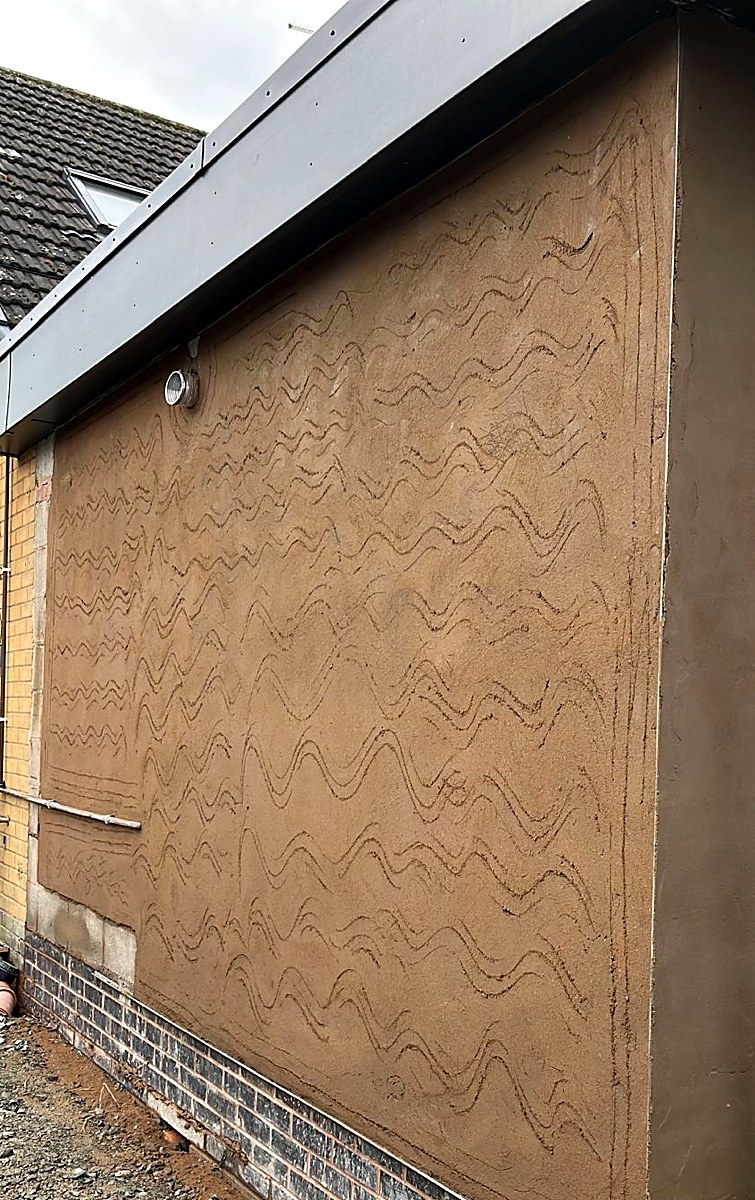 Scratch coat render applied to an extension wall