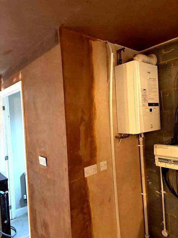 Pipework boxed in and the wall skimmed beside the boiler in Stafford